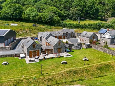 An outdoor space with multiple buildings and a garden at The Barn in Corwen