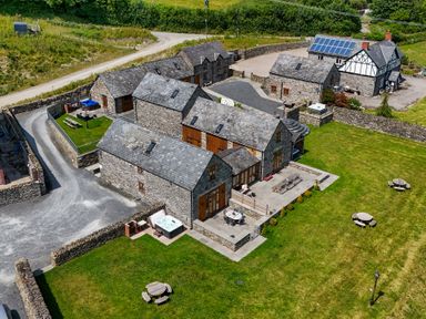 An outdoor area with stone buildings and furniture at The Barn in Corwen