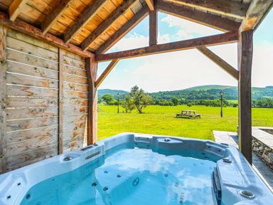 A hot tub under a wooden structure in an outdoor area at The Barn in Corwen