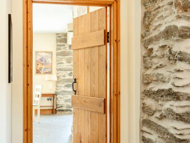 A wooden door opening to a hallway with a table and chair at The Barn in Corwen