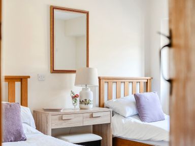 A bedroom with two beds and a lamp on a table at The Barn in Corwen