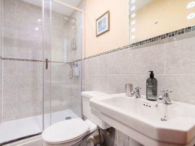 A bathroom featuring a shower, toilet, and sink at The Barn in Corwen