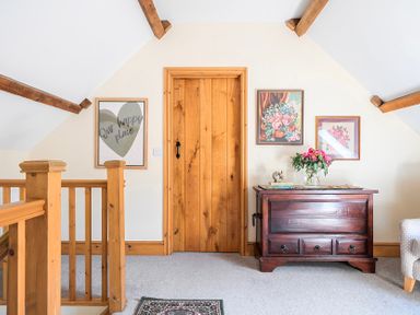A landing area with a wooden door and artwork on the wall at The Barn in Corwen