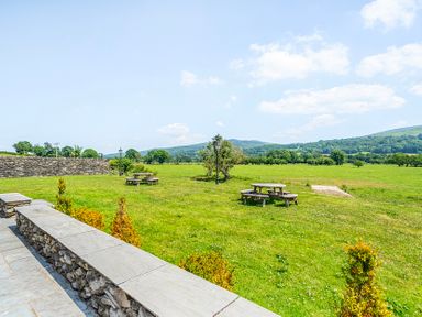 A garden with tables and benches at The Barn in Corwen