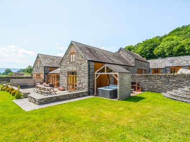 A house with a hot tub and patio furniture in the garden at The Barn in Corwen