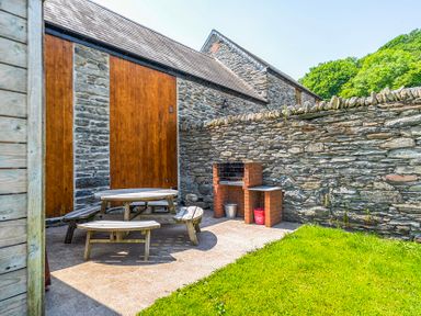 An outdoor space with a table and benches at The Barn in Corwen