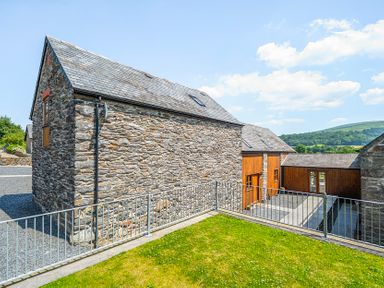 An outdoor area with stone and wooden houses at The Barn in Corwen