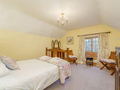 A bedroom with a double bed two chairs curtains and a dresser at The Druids in Druid near Corwen