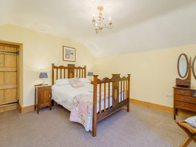 A bedroom with a wooden bed a side table with lamp a wooden dressing table with mirror at The Druids in Druid near Corwen