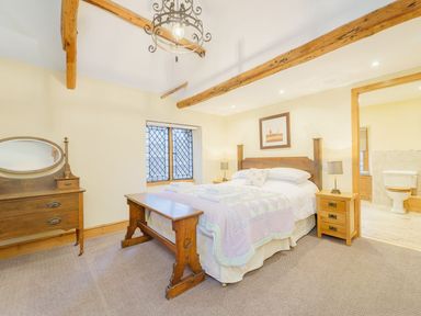 A bedroom with a wooden bed and bench and an adjoining bathroom at The Druids in Druid near Corwen