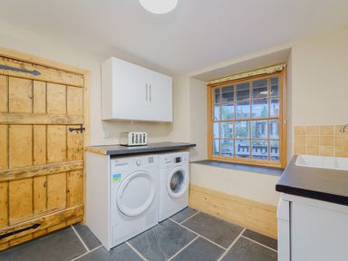 A laundry room with washing machine dryer wooden door and large window at The Druids in Druid near Corwen
