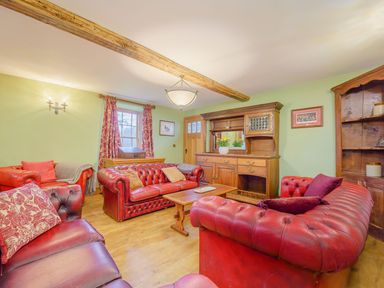 A living room with red leather sofas wooden furniture and green walls at The Druids in Druid near Corwen