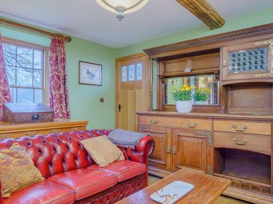 A living room with a red leather sofa wooden furniture and yellow flowers at The Druids in Druid near Corwen
