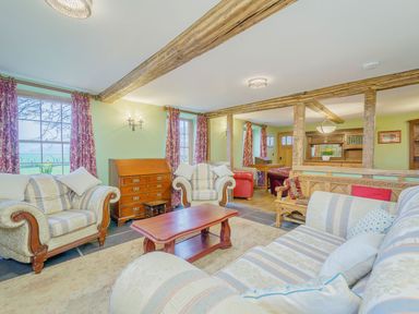A sitting room with striped armchairs sofas wooden coffee table and exposed beams at The Druids in Druid near Corwen
