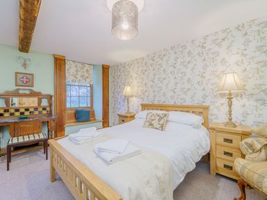 A bedroom with a wooden bed and bedside tables with lamps at The Druids in Druid near Corwen