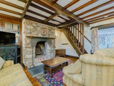 A living room with stone fireplace wooden ceiling beams and staircase at The Druids in Druid near Corwen