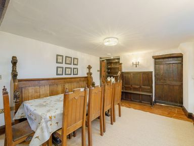 A dining room with wooden chairs a table with a tablecloth wooden door and paneling at The Druids in Druid near Corwen