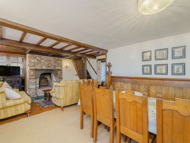 A living room with wooden dining chairs a dining table and a stone fireplace at The Druids in Druid near Corwen