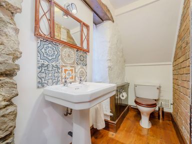 A bathroom with a white sink and mirror above it next to a toilet with a wooden seat at The Druids in Druid near Corwen