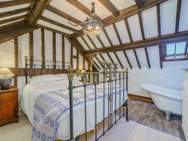 A bedroom with a metal bed frame bedside tables with lamps and a clawfoot bathtub at The Druids in Druid near Corwen