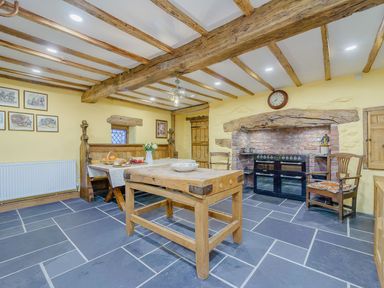 A kitchen with wooden beams on ceiling stone floor wooden dining table and bench seating at The Druids in Druid near Corwen