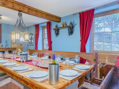 A dining room with long wooden table set with plates glasses and wine at The Druids in Druid near Corwen