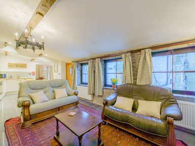 A living room with two leather sofas a wooden coffee table and floral curtains at The Druids in Druid near Corwen