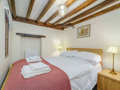 A bedroom with a bed with white bedding and towels on a red blanket at The Druids in Druid near Corwen