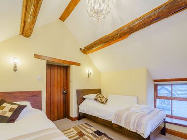 A bedroom with two single beds under wood ceiling beams at The Druids in Druid near Corwen