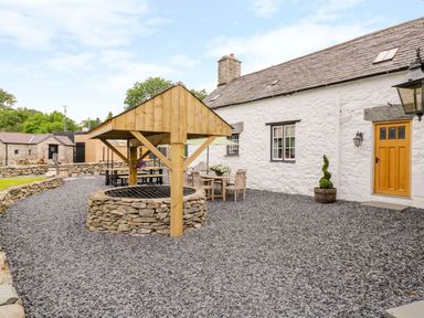 A stone courtyard with a wooden covered well and outdoor seating at The Druids in Druid near Corwen