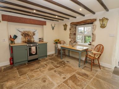A kitchen with a stove and table at The LA'AL Cragg in Kirkby Stephen