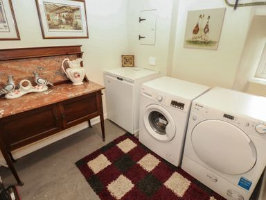 A laundry room with a washer, dryer and sideboard at The LA'AL Cragg in Kirkby Stephen