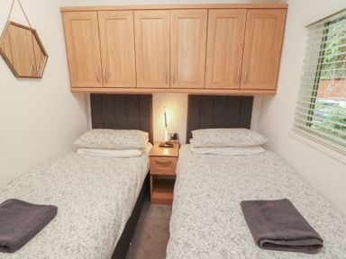 A bedroom with two beds and a bedside table at Willows Lodge, White Cross Bay, near Windermere