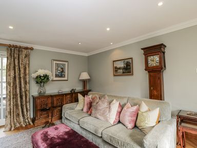 A living room with a green sofa and decorative items at The Old Hall in Tetbury