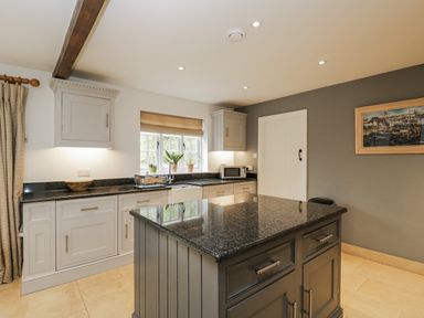 A kitchen with cabinets, microwave, and granite countertops at The Old Hall in Tetbury