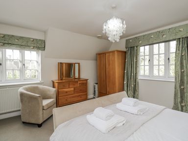 A bedroom with a bed and armchair at The Old Hall in Tetbury