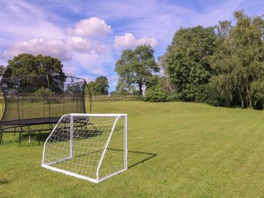 A trampoline and soccer goal on grass at The Old Hall in Westonbit Nr Tetbury