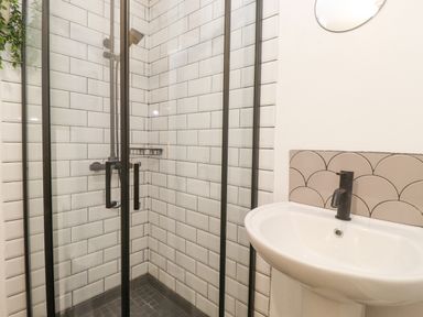 A bathroom with a glass shower enclosure and a white sink with a black faucet at The Wonky Burrow in Bowness-On-Windermere