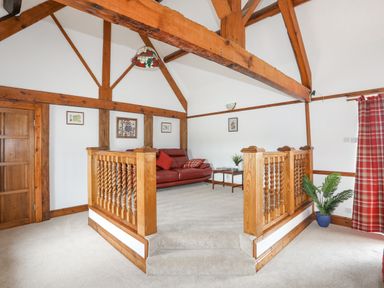 A sitting area with a red sofa coffee table and framed pictures on the wall at Caerdegog Ganol in Cemlyn near Cemaes Bay