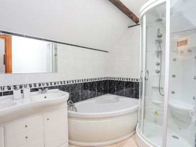 A bathroom with a corner bathtub a shower cubicle and a double sink vanity at Caerdegog Ganol Cemlyn near Cemaes Bay