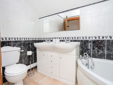 A bathroom with a toilet sink cabinet and bathtub at Caerdegog Ganol in Cemlyn near Cemaes Bay