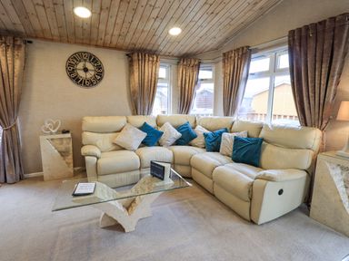 A corner living room with cream leather sofas and blue cushions at Our Happy Place Lakeside 16 Borwick near Carnforth