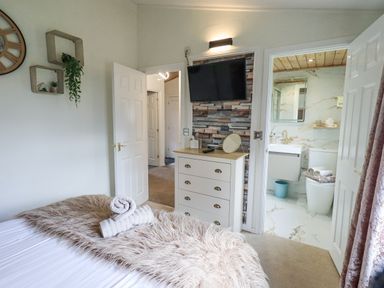 A bedroom with a bed a chest of drawers and an open door leading to a bathroom at Our Happy Place Lakeside 16 Borwick near Carnforth