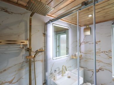 A bathroom with a shower, sink, illuminated mirror, and toilet at Our Happy Place Lakeside 16 Borwick near Carnforth