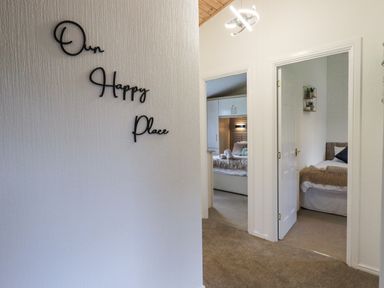 A hallway with two open bedroom doors and a wall sign reading Our Happy Place at Our Happy Place Lakeside 16 Borwick near Carnforth