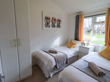 A bedroom with two single beds bedside table lamp and wardrobe at Our Happy Place Lakeside 16 Borwick near Carnforth