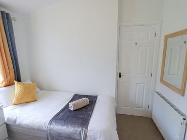 A bedroom with a bed a pillow folded towel white door radiator and mirror at Our Happy Place Lakeside 16 Borwick near Carnforth