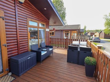 A wooden deck with outdoor seating and a planter at Our Happy Place Lakeside 16 Borwick near Carnforth
