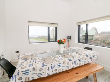 A dining room with a table set for meals and windows showing building exteriors at Old Field House in Slade near Fethard-On-Sea County Wexford