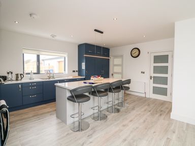 A kitchen with a central island and four chairs at Old Field House in Slade near Fethard-On-Sea County Wexford